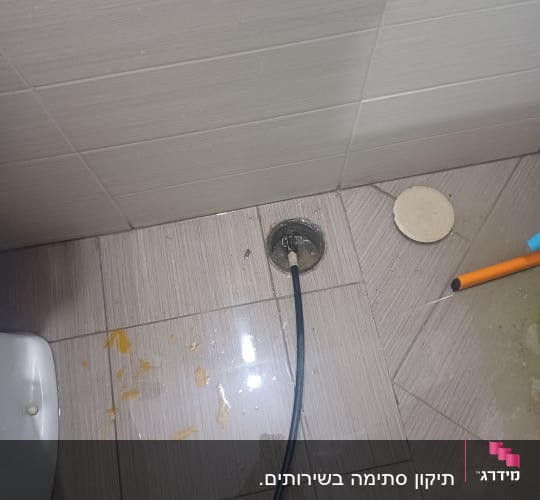 כבל שחור מחובר לניקוז ברצפה רטובה